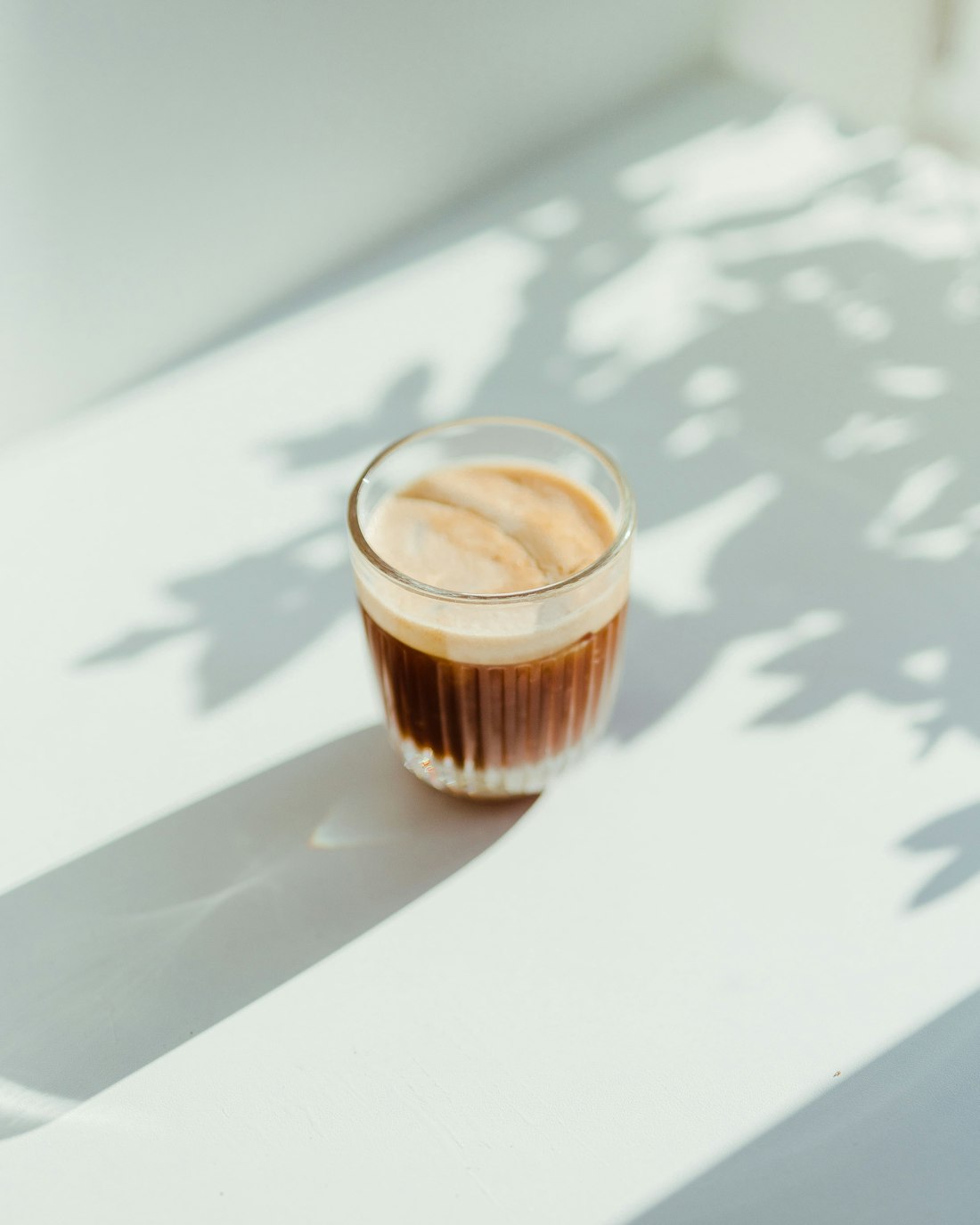 A cortado in a small glass in sunlight